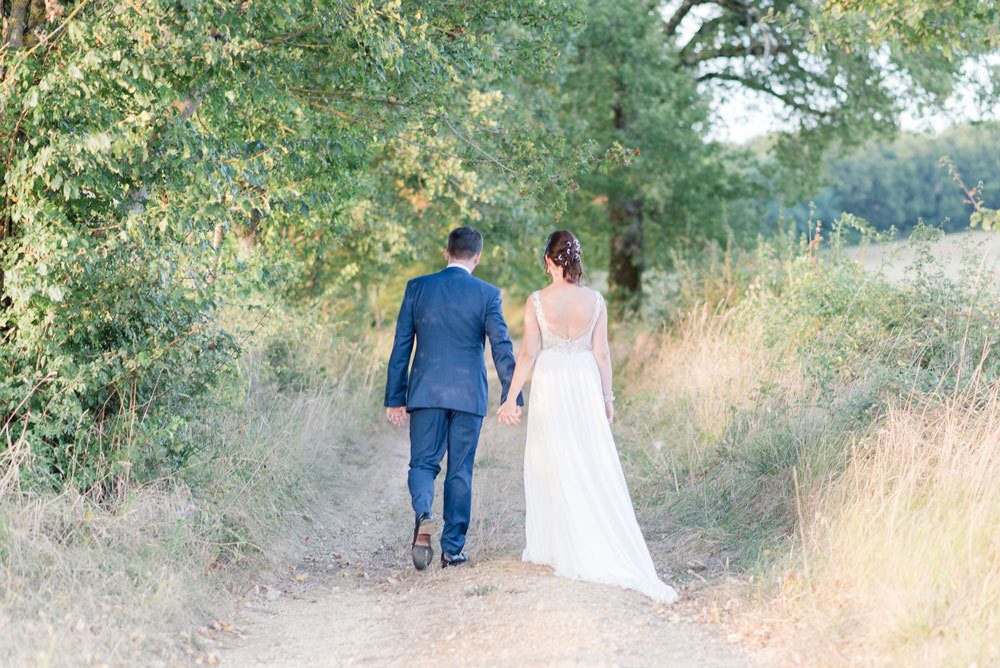 Un couple de mariés se promène dans un chemin de campagne