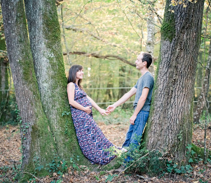 Couple de futurs parents se tenant la main entre deux arbres