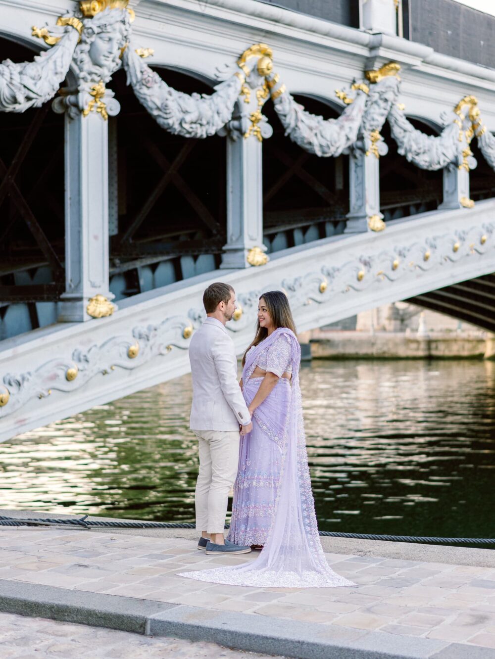the couple holding hands below the bridge, near the Seine river