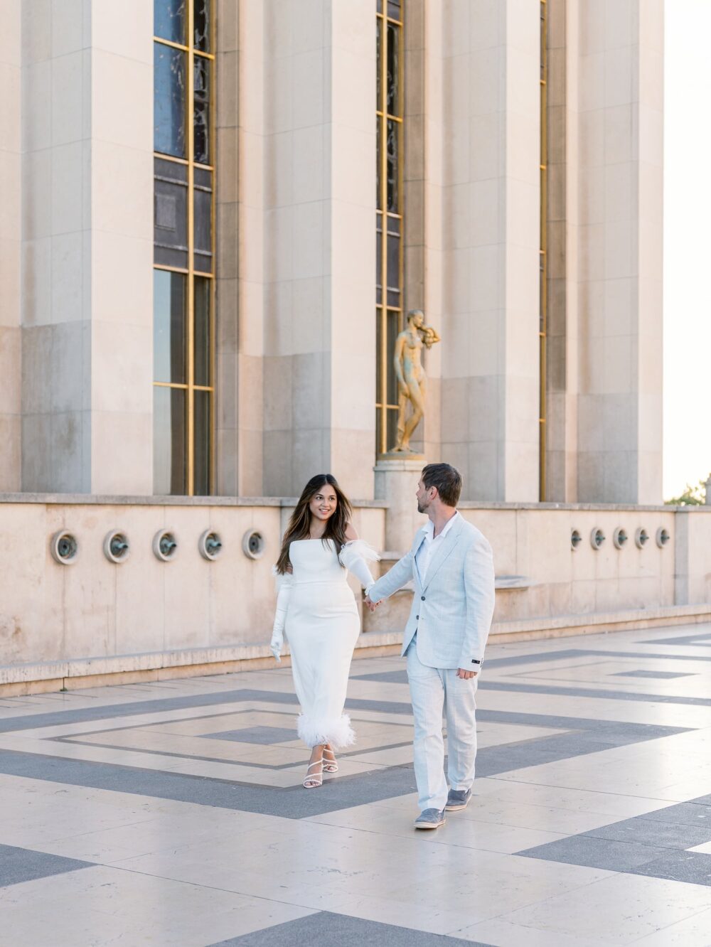 couple walking near the golden statues of trocadero