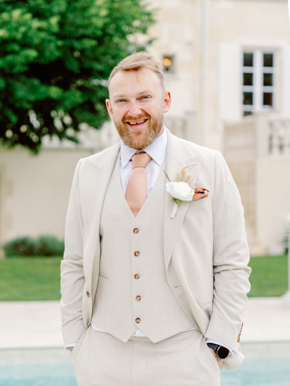 Portrait of the groom wearing a beige suit with a pink/peach tie