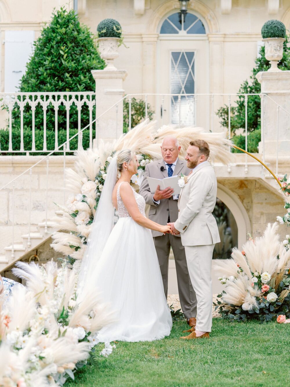 Bride and groom holding hands with the officiant behind