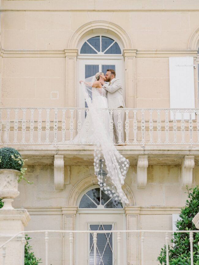 Bride and groom on a balcony of chateau n°3 with the veil hanging