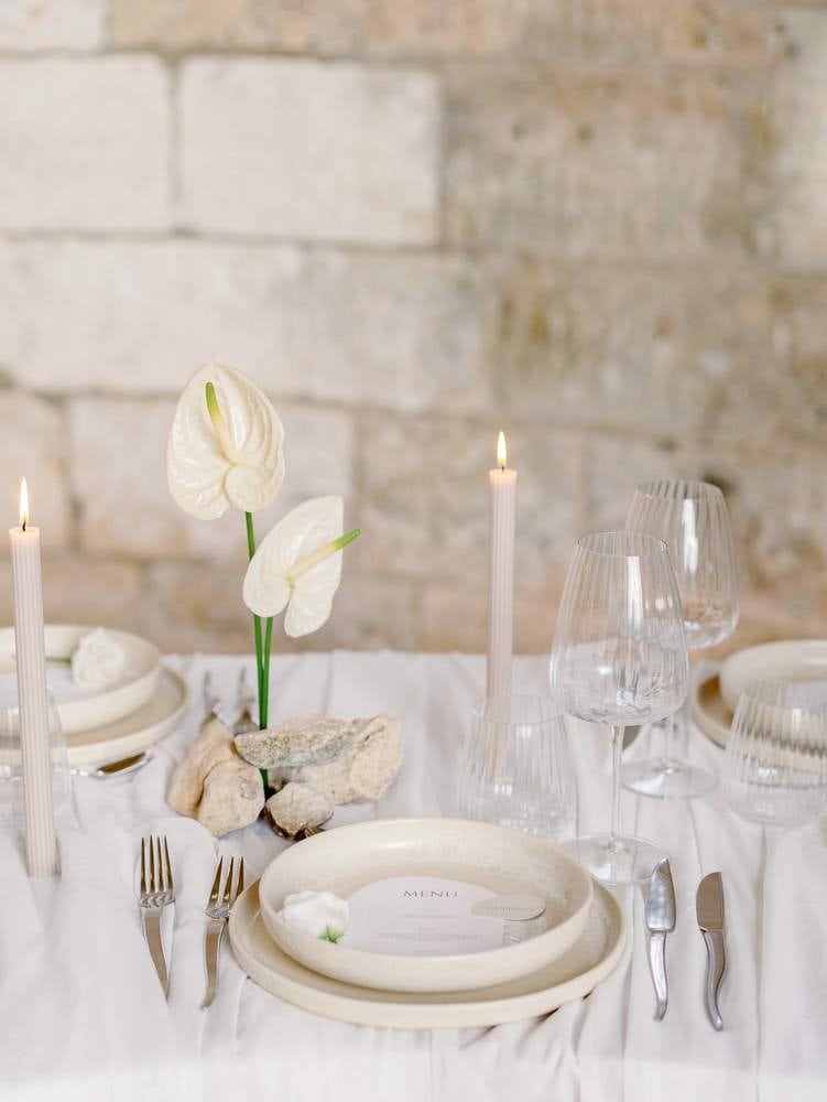 wedding table with white tablecloth and beige plates and candles