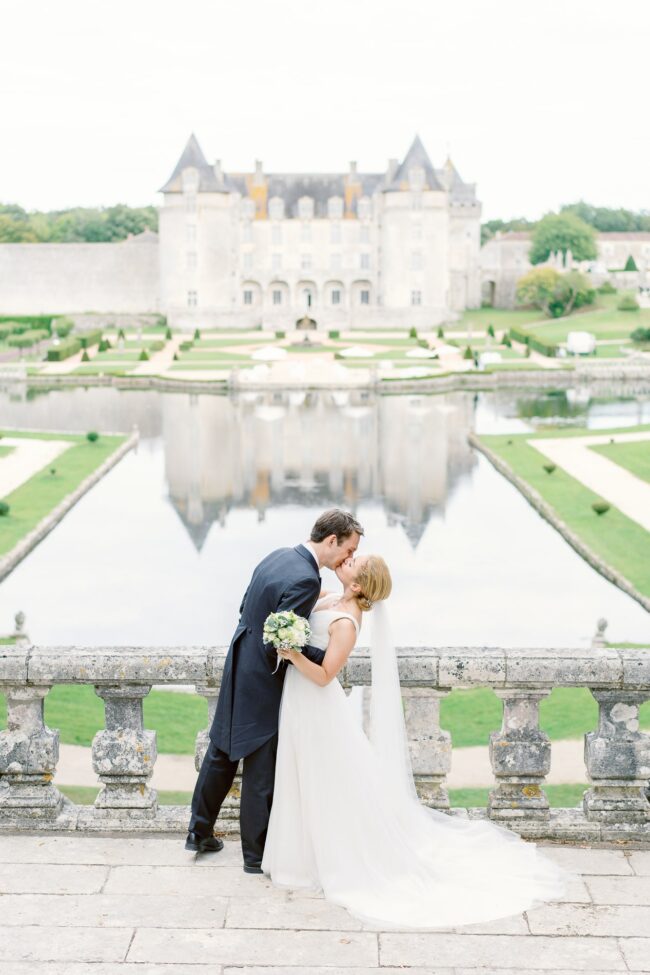 Bride and groom kissing in front of a french chateau