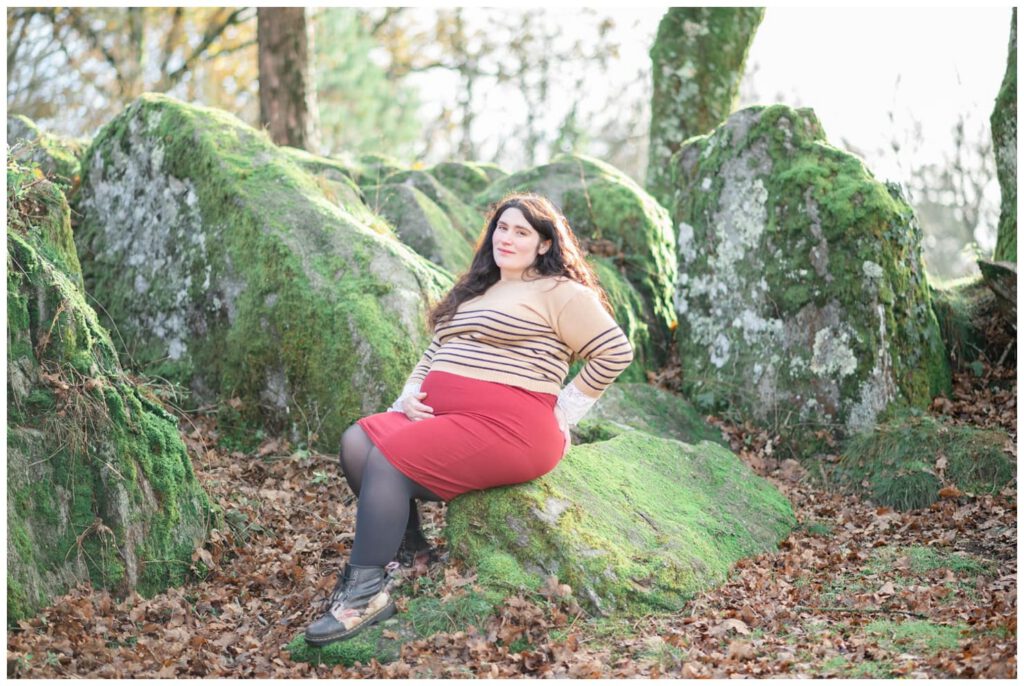 Femme enceinte en jupe rouge sur des rochers couverts de mousse
