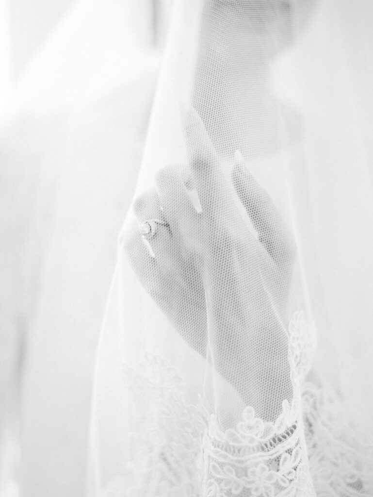 Main d'une mariée sous son voile, en noir et blanc