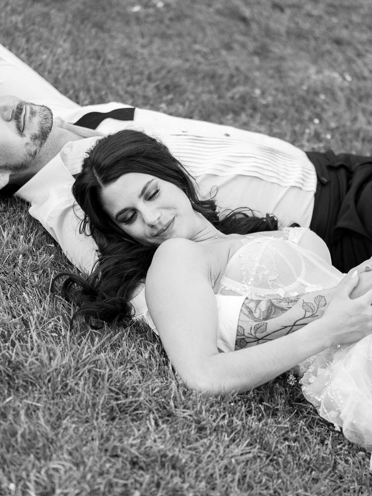 bride and groom laying on the grass