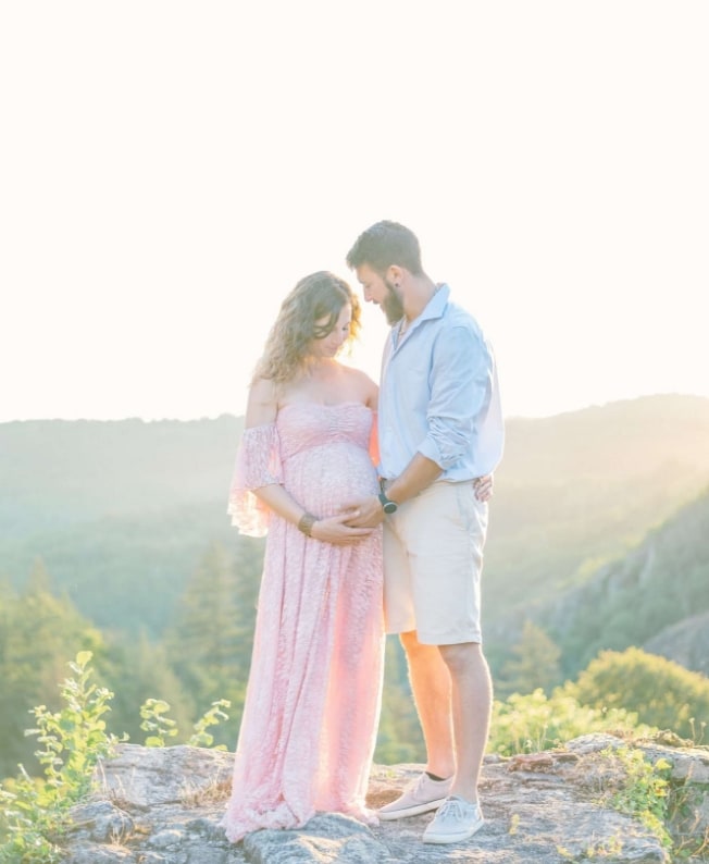Couple de futurs parents sur un rocher avec vue sur des collines
