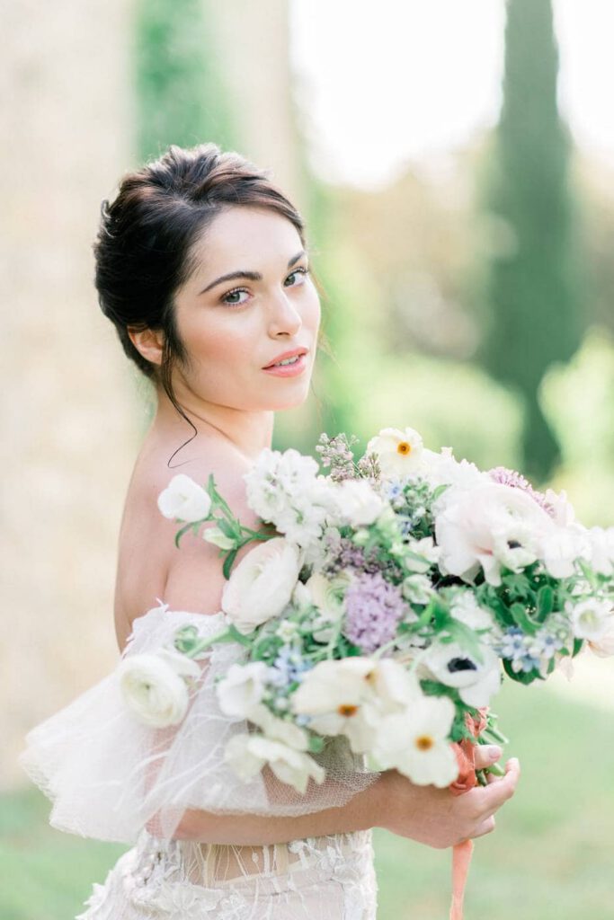 portrait d'une mariée avec un gros bouquet dans les tons blanc, vert et mauve