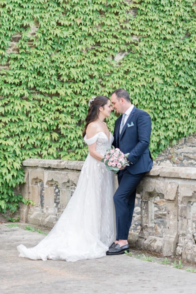 photos de couple de mariés sur un muret avec du lierre