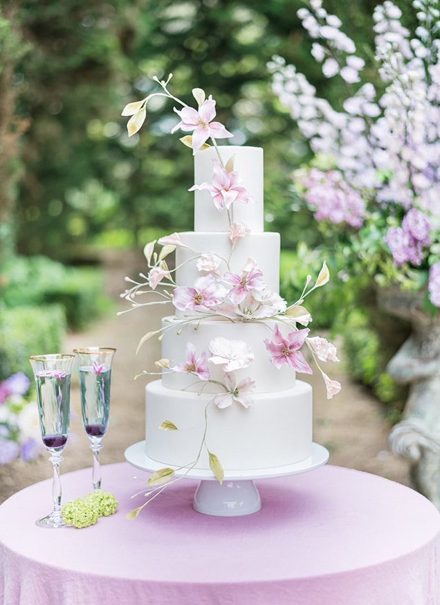 white wedding cake decorated with purple flowers