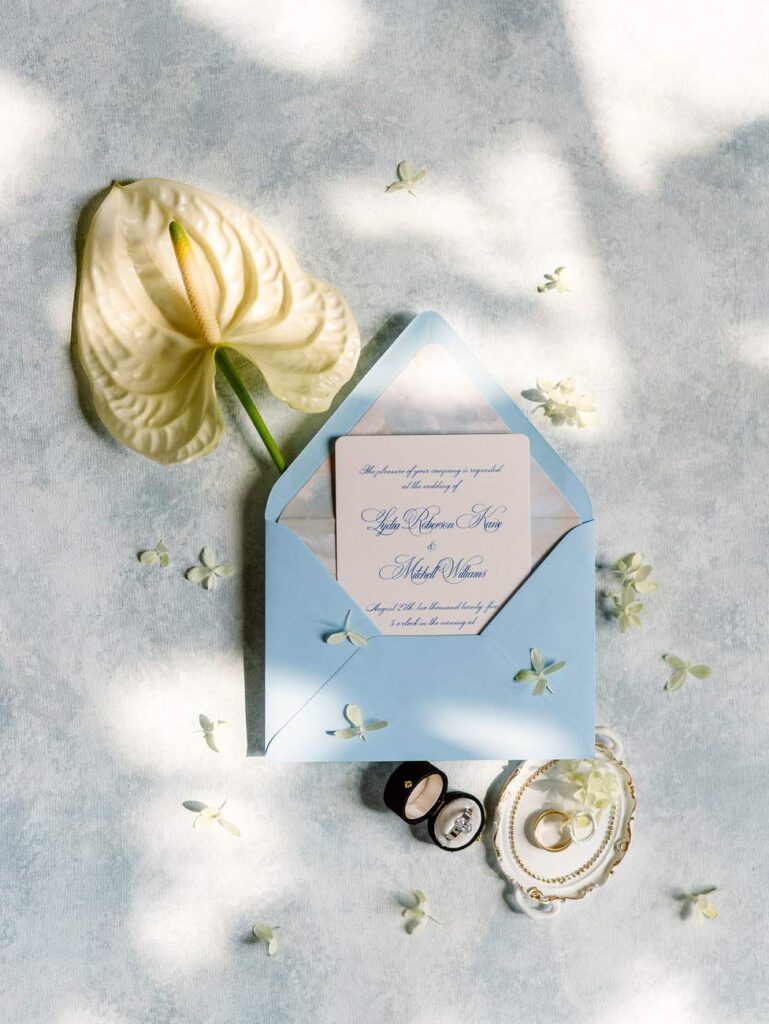 wedding invitation with a blue enveloppe, rings and an arum flower