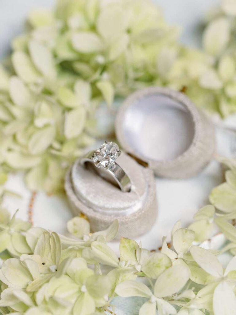 wedding ring in a beige box surrounded by flower petals