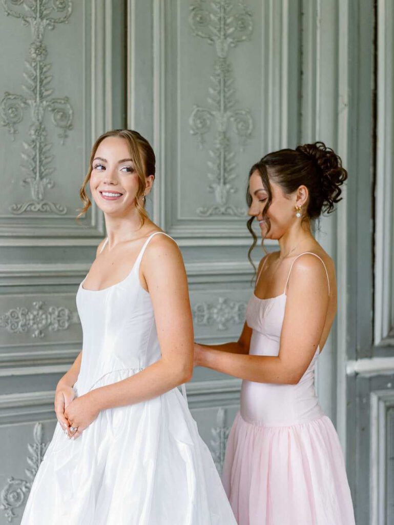 bride getting dressed with her sister