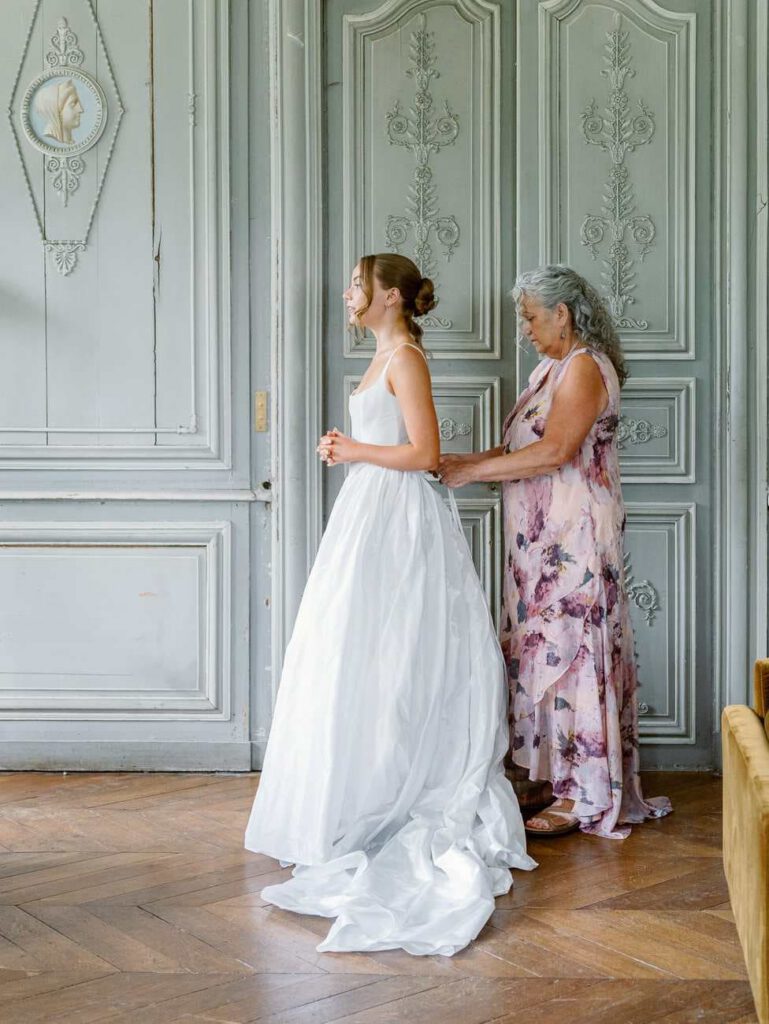 bride getting dressed with her mother