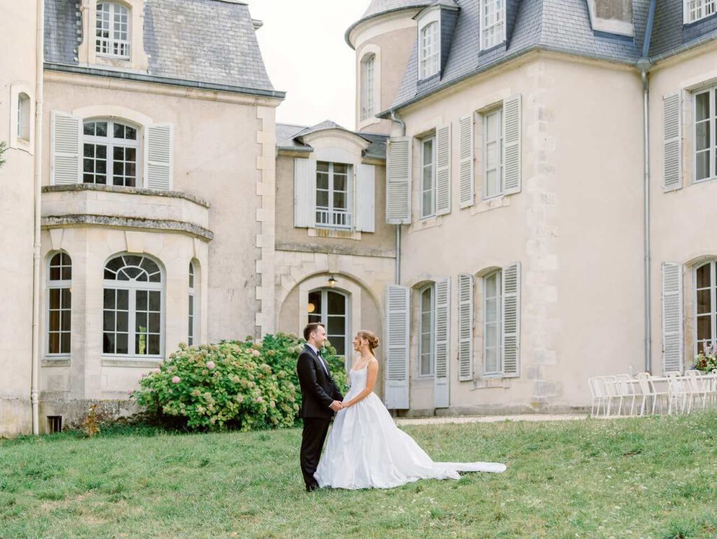 Bride and groom standing in front of Château de Thauvenay