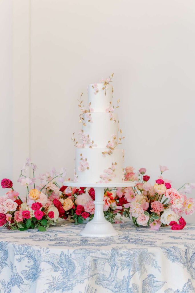 White wedding cake with golden leaves and pink flowers