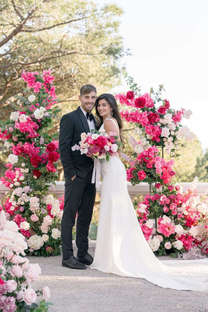 Wedding ceremony at castel bay with a big arch made with pink, magenta, fushia bold flowers