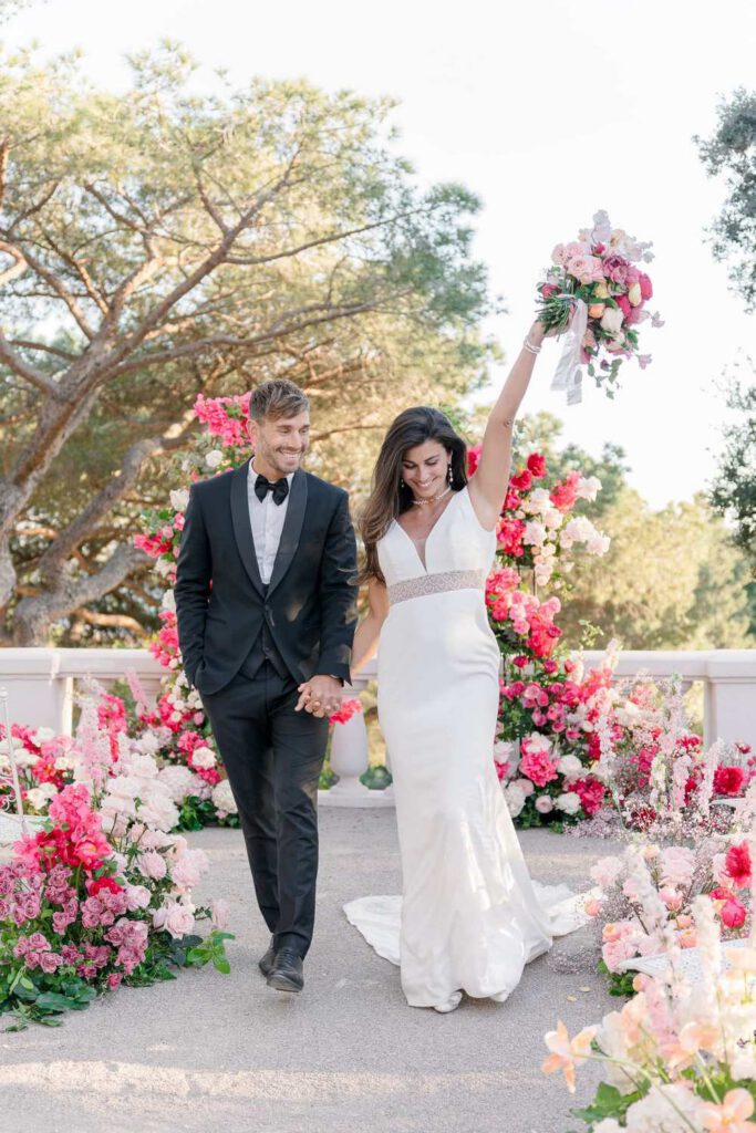Wedding ceremony at castel bay with a big arch made with pink, magenta, fushia bold flowers