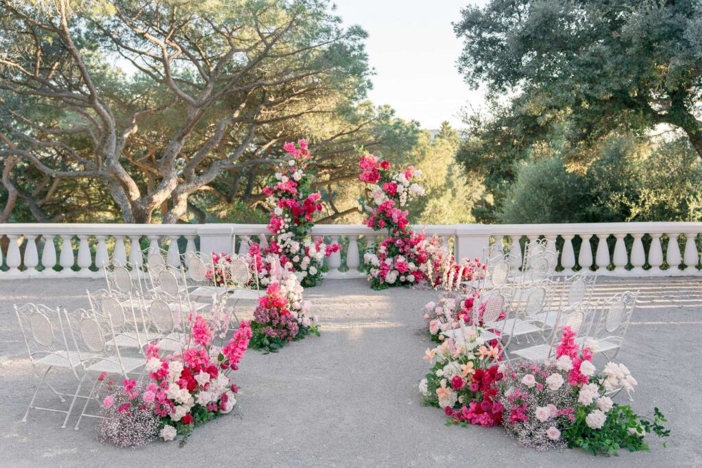 Wedding ceremony at castel bay with a big arch made with pink, magenta, fushia bold flowers