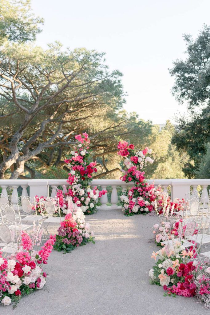Wedding ceremony at castel bay with a big arch made with pink, magenta, fushia bold flowers