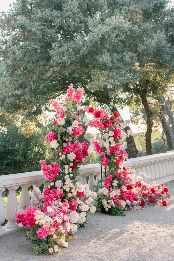 Wedding ceremony at castel bay with a big arch made with pink, magenta, fushia bold flowers