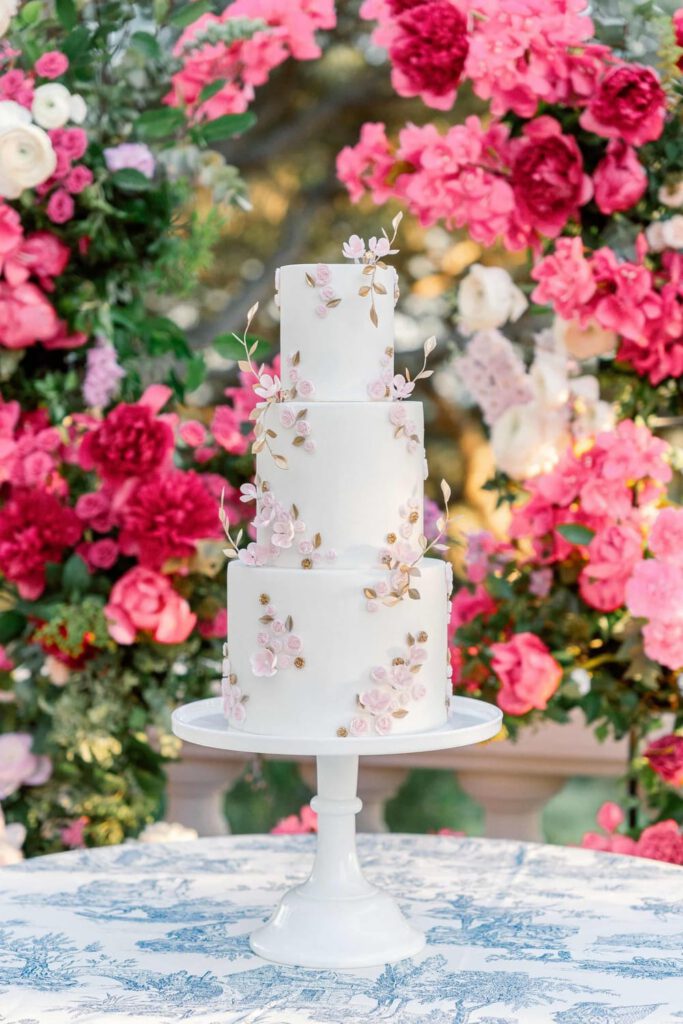 White wedding cake with golden leaves and pink flowers
