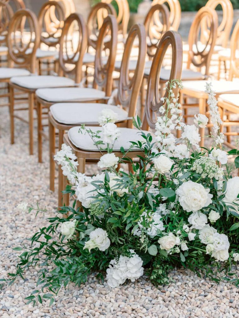 Wedding ceremony with a chuppah decorated with white flower and green foliage at Château de Fontarèches