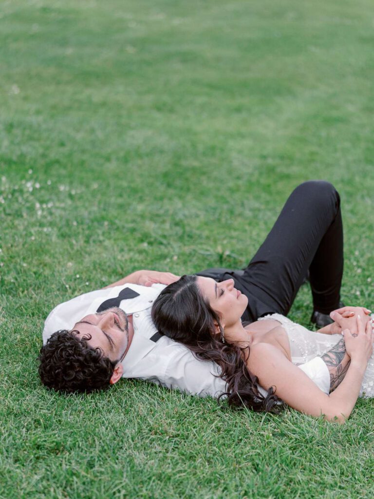 bride and groom laying in the grass