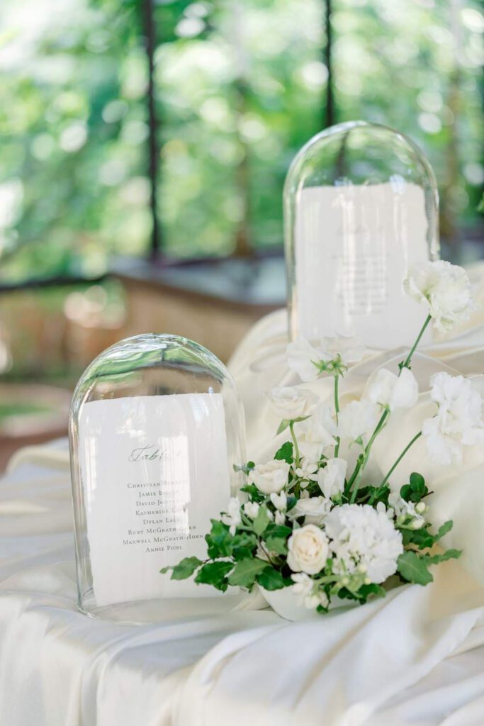 wedding seating chart with white silk tablecloth, white flowers and foliage