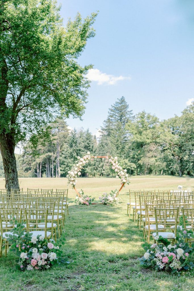 wedding ceremony in the garden of the chateau with an arch and flowers