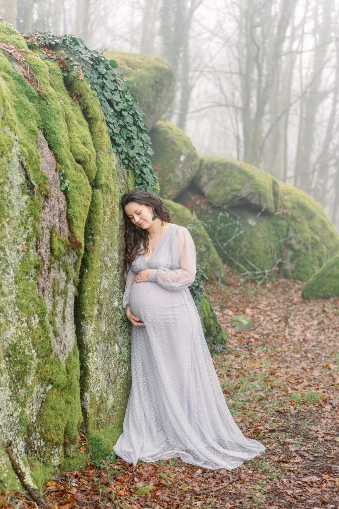 femme enceinte contre un rocher couvert de mousse