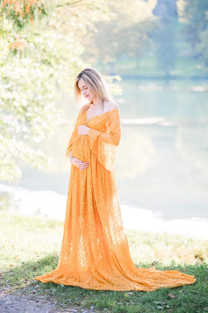 femme enceinte en robe orange au bord d'un lac