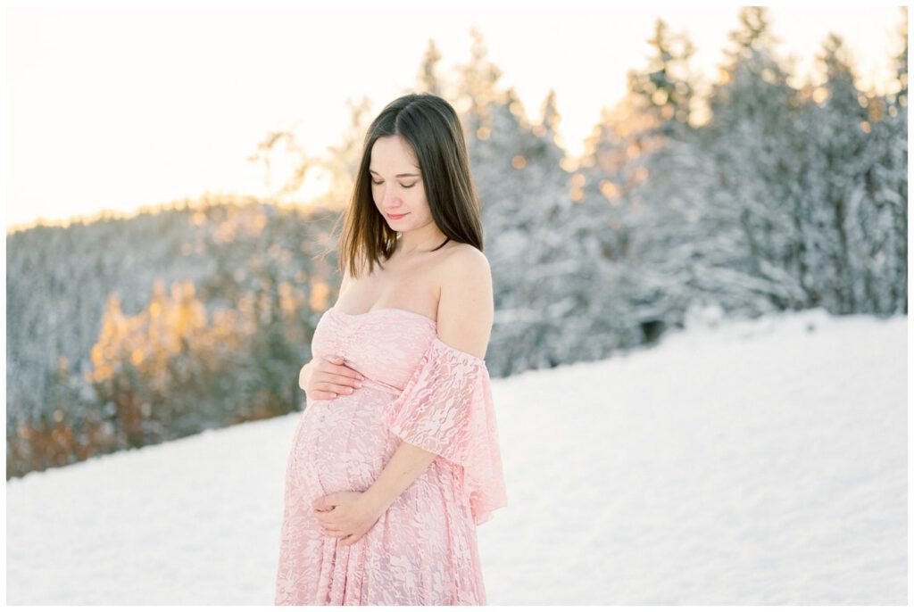 séance grossesse dans la neige avec une robe rose