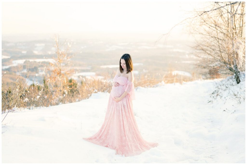 séance grossesse dans la neige avec une robe rose