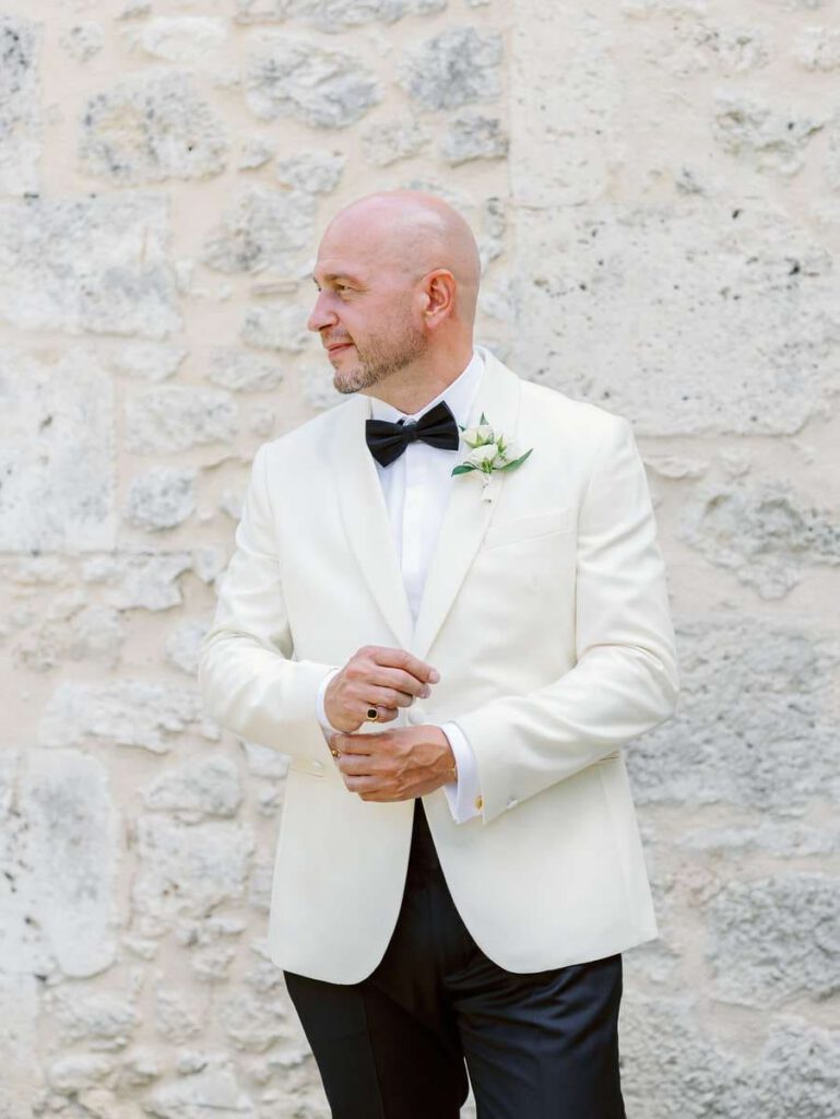 groom portrait at clos des charmes with a white jacket and white boutonniere and black bow tie