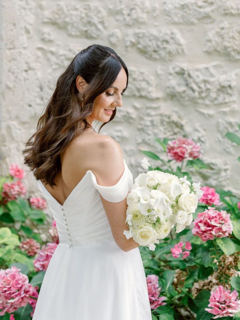 Bride portrait in front of a stone wall and pink flowers at clos des charmes