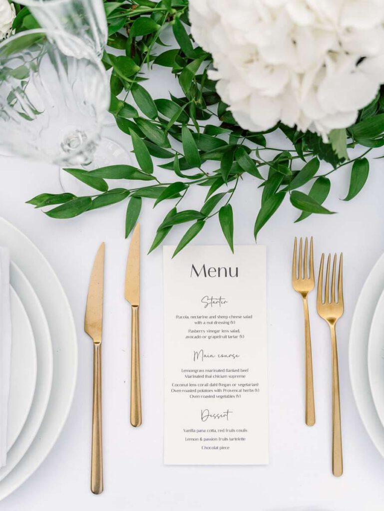 wedding table at clos des charmes with a white tablecloth, white flowers, foliage, golden cutlery