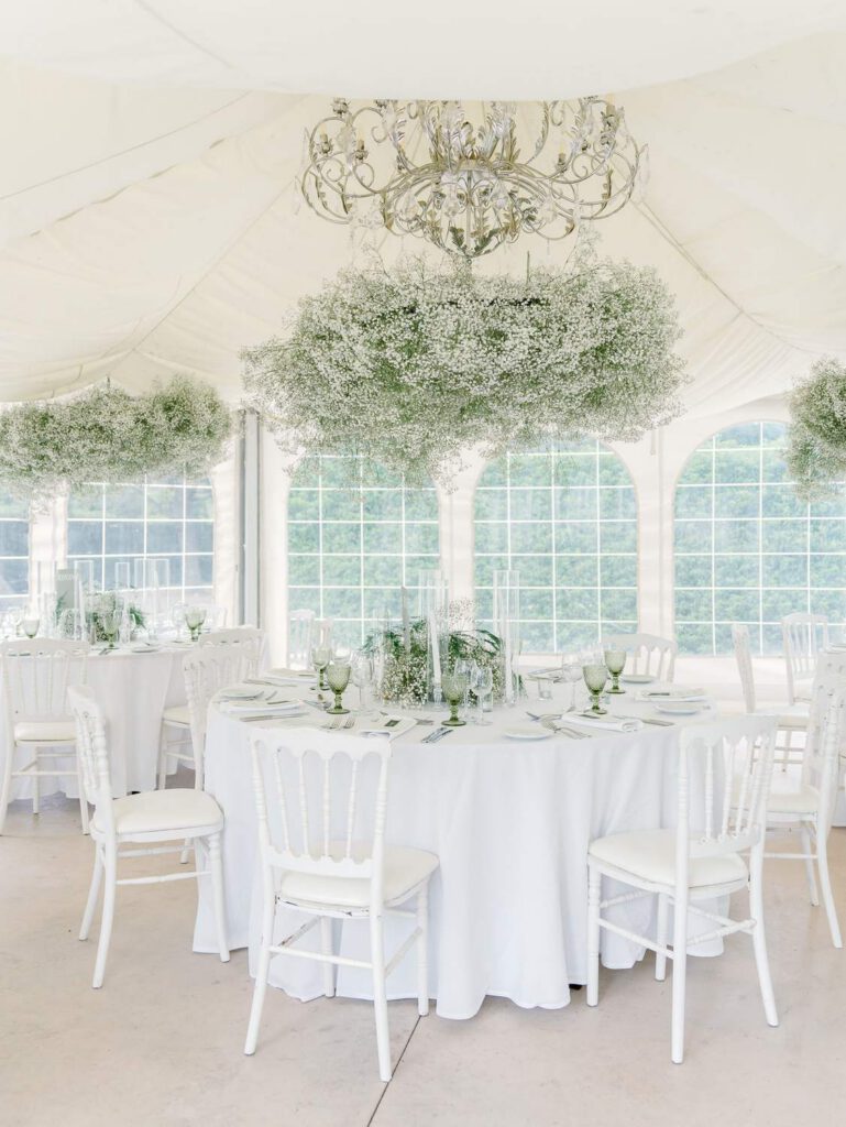 Wedding dinner tables at Domaine d'Essendieras with white chairs and tablecloth and Gypsophila flowers hanging on the ceiling