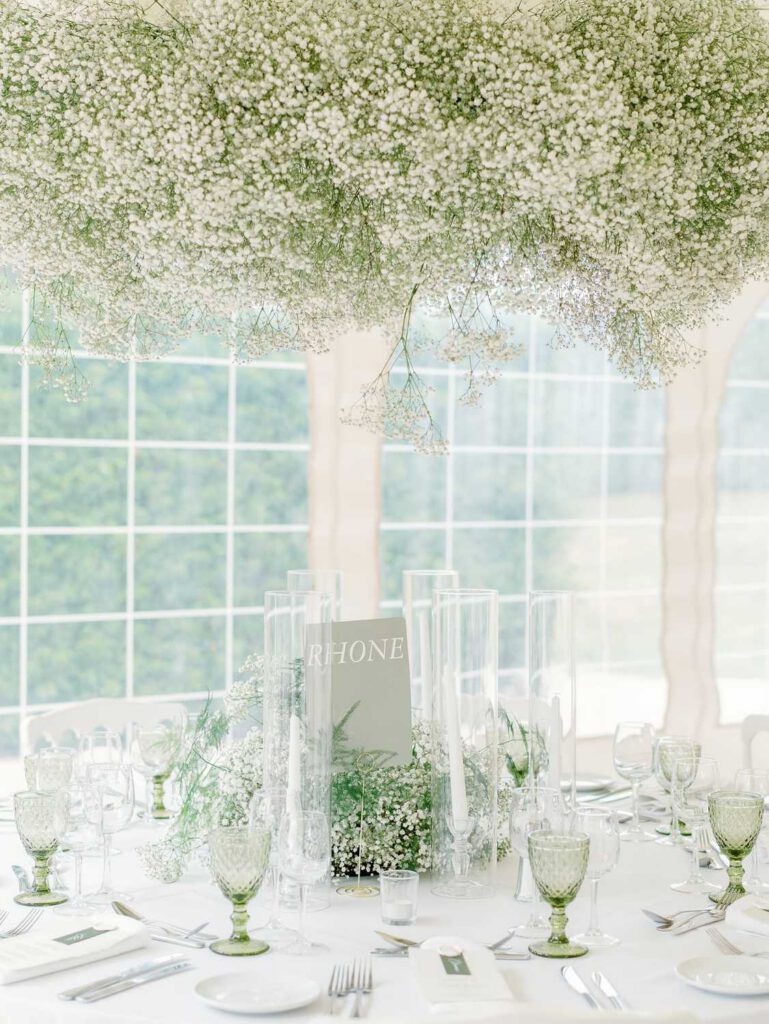 Wedding dinner tables at Domaine d'Essendieras with white chairs and tablecloth and Gypsophila flowers hanging on the ceiling