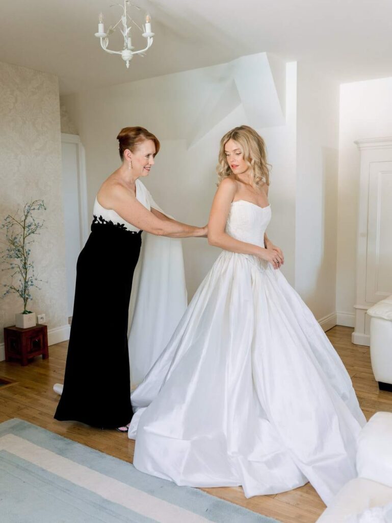 bride getting dressed with her mother