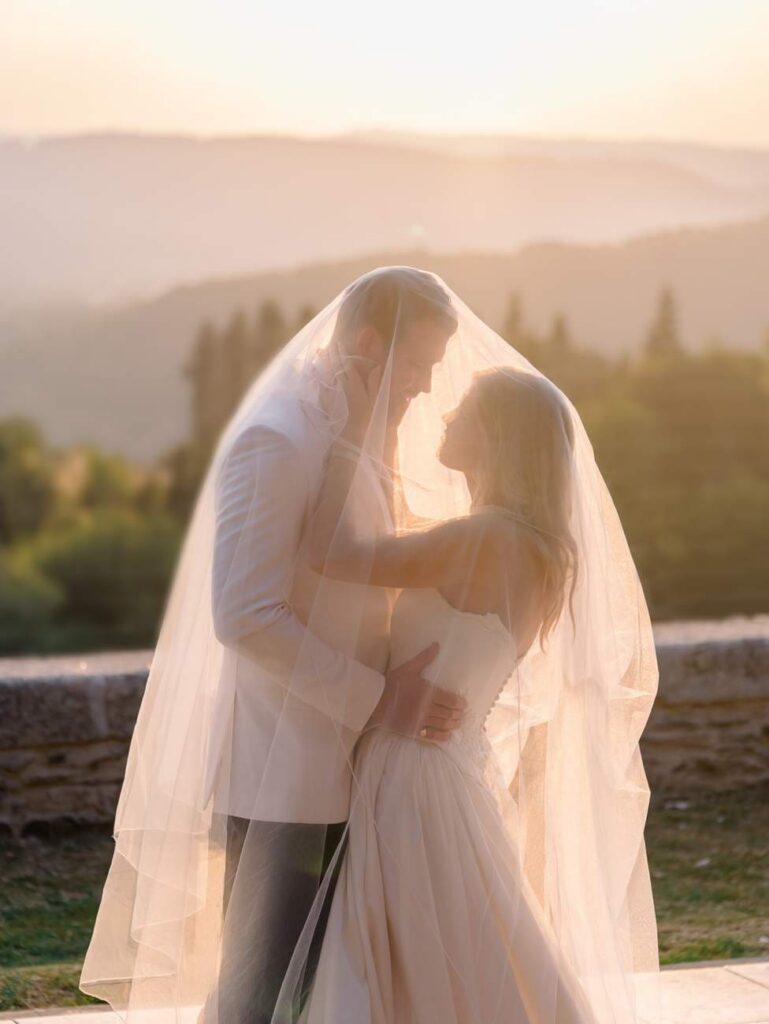 bride and groom under a veil at sunset